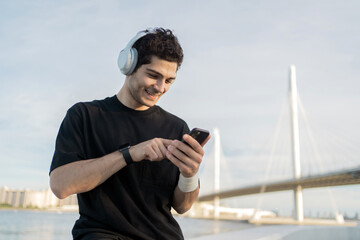 Uses a fitness app on the phone, listens to music, a male athlete runner does a workout.
