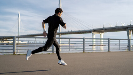 Runner male athlete running does a workout exercise in the city, uses a fitness watch