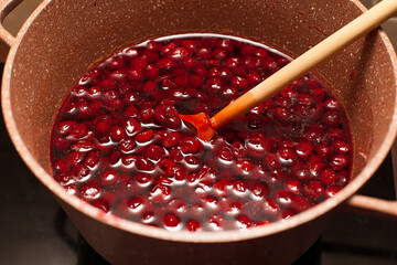 Cooking pot with sweet cherry jam on grunge background.