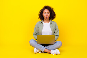 Naklejka premium Full body photo of attractive young girl wavy hair impressed netbook fast wifi wear stylish khaki look isolated on yellow color background