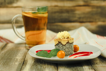 A piece of cake on a white plate and decorated with fruits and sauces