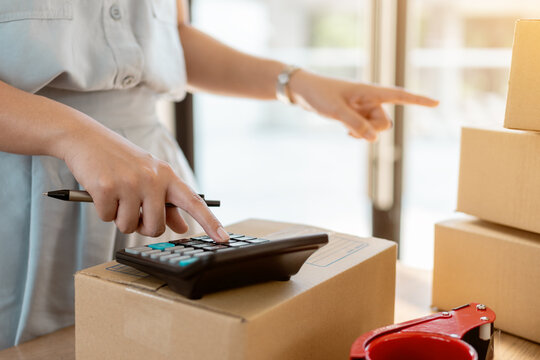 Close up online business owner using calculator for calculating financial expense.