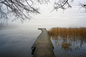 Misty morning with empty landscape and wooden pier