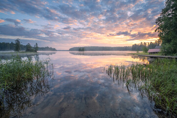 Beautiful sunrise in tranquil lake at summer evening in Finland with pier - 522456975