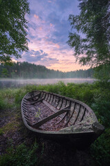 Beautiful sunrise in tranquil lake at summer evening in Finland with wooden boat - 522456978