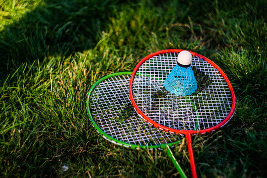 Close-up of two badminton racquets and a shuttlecock on the grass in summer