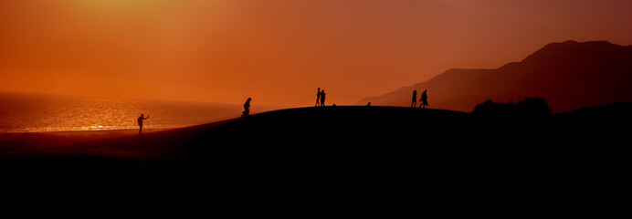 Fototapeta na wymiar Silhouette view of people walking on the sand hill at sunset, people watching the sunset on the sand hill in Patara, Antalya, Turkey