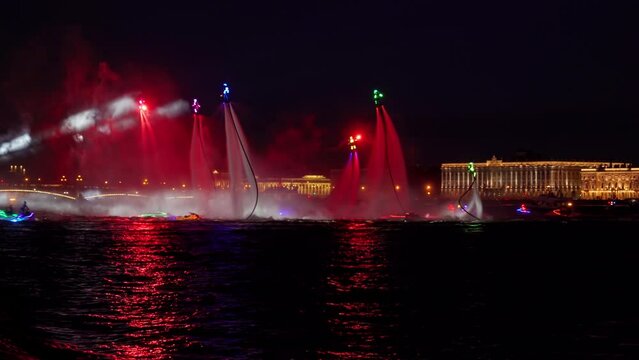 A lot of flyboarders and brightly dressed up jet skiers perform their show at a holiday in the center of St. Petersburg at night, water activities