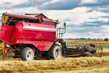 Obraz premium Combine in the field harvests wheat against the blue sky. Close-up.