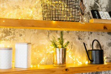Kitchen cooking utensils in ceramic storage pot and Christmas decor on a shelf on a rustic wooden wall.