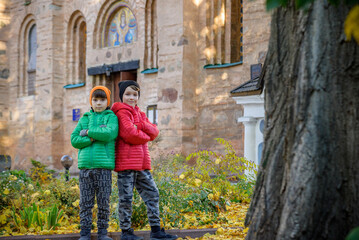 Obraz na płótnie Canvas Young brothers near an ancient stone church. Kids smiling and ha