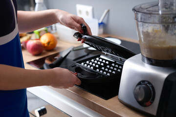Person opens electric waffle iron in kitchen
