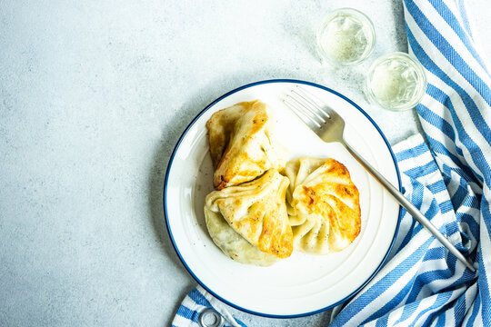 Overhead view of a plate of fried Georgian khinkali and two glass of traditional Georgian chacha