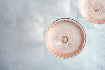 Overhead view of two glasses of pink champagne in champagne coupe glasses