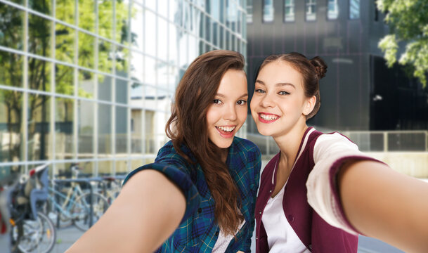 people and friendship concept - happy smiling pretty teenage girls taking selfie over city street or school yard background