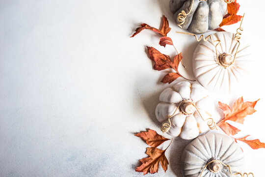 Overhead view of ornamental ceramic pumpkin decorations on a table with autumnal leaves