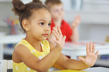 A Black girl listens attentively to the teacher in the classroom