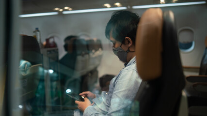 A man wearing face mask while sitting into an airplane. New normal traveling during a pandemic....