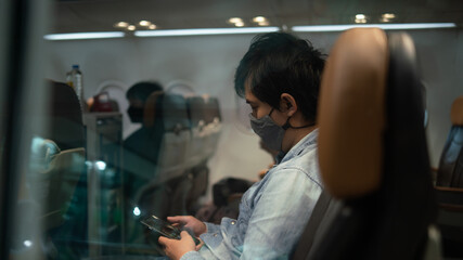 A man wearing face mask while sitting into an airplane. New normal traveling during a pandemic....