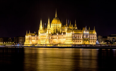 Fototapeta na wymiar Lighted Hungarian parliament building at night and flowing river Dunube. Long exposure photo
