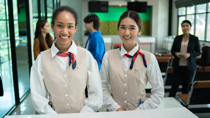Portrait of beautiful Asian woman airport ground attendant in uniform and standing smile at counter check in. ground hostess airport reception at airline check in counter staff.