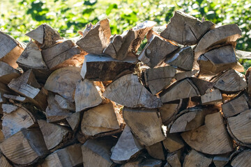 Rustic wooden logs, stack of outdoor firewood pile. Morning sunlight casting through the logs, creating a textured backdrop.