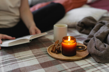 Young woman reading book while sitting in lotus pose on bed in cozy bedroom, spending leisure time at home.