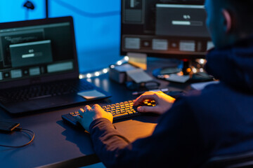cybercrime, hacking and technology concept - close up of male hacker in dark room writing code or...