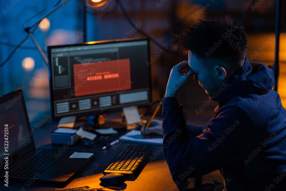Poster cybercrime, hacking and technology concept - male hacker in dark room writing to notebook and using 
