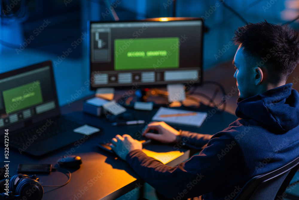 Poster cybercrime, hacking and technology concept - male hacker in dark room writing code or using computer
