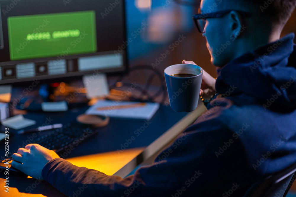 Poster cybercrime, hacking and technology concept - close up of male hacker in dark room drinking coffee an