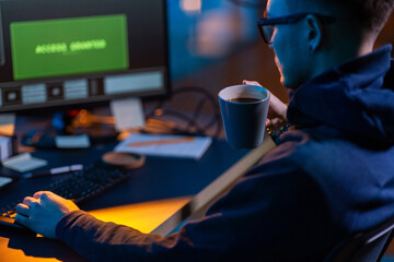 cybercrime, hacking and technology concept - close up of male hacker in dark room drinking coffee...