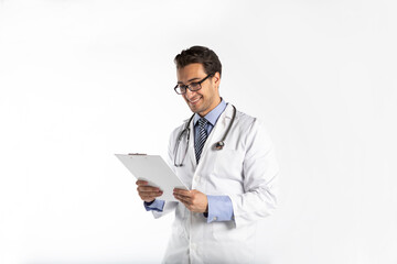 Naklejka na ściany i meble Portrait of handsome positive doctor in medical gown and stethoscope holding tablet and smiling isolated on white background