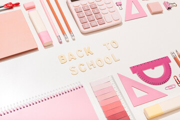 Lettering back to school on a pink background with school supplies
