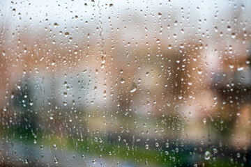 Naklejka na ściany i meble Raindrops on window glass. Rainy city background. Rainy autumn weather