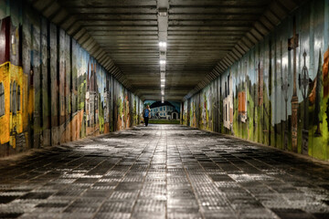 Pedestrians walking in long underpass with graffitti on walls in town Liptovsky Hradok, Slovakia - Powered by Adobe
