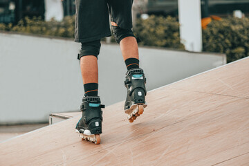 Close-up of the legs of a roller skater performing tricks and just riding on the ramp in urban sports park. Teenage hobby concept
