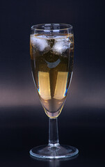 Champagne glass with ice cubes on a black background, close-up