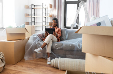 moving, people and real estate concept - happy smiling woman with tablet pc computer and boxes at...