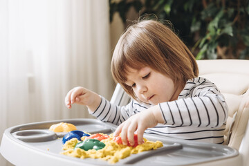 Cute little boy playing with kinetic sand. Development of fine motor skills. Early sensory education. Activities Montessori. Sensory plays at home.