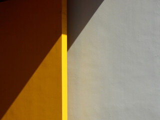 yellow wood door and white concrete wall background with shadow of sunlight