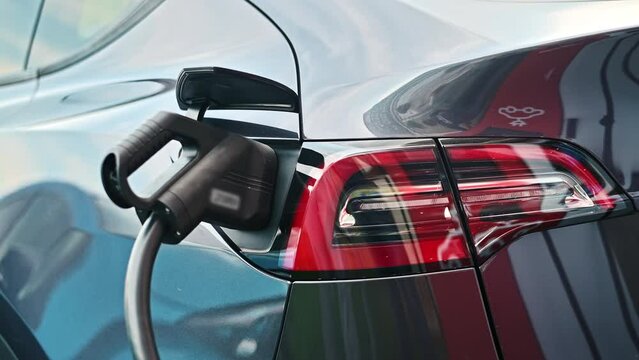 Close view of a charger plugged into an electric car at a charging station