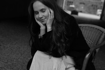 Sensual portrait of a young brunette in a white dress. Girl in a autumn wear is sitting in a chair 