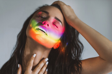 Closeup portrait of smiling woman with ray of rainbow light on her face. Rainbow optical flare from...