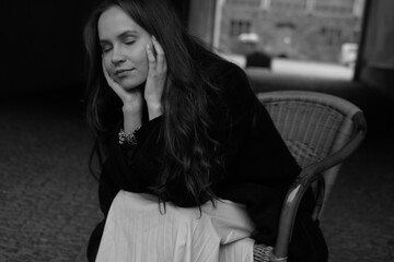 Sensual portrait of a young brunette in a white dress. Girl in a autumn wear is sitting in a chair 