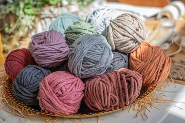 Basket with colorful, cozy cotton twine balls. Homely atmosphere. Hobby knitting. Cotton twines in warm colors. Blurred background. Excellent image for handcrafts banners and advertisements.