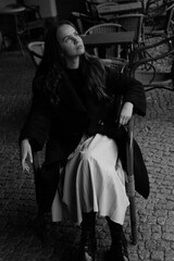 Fototapeta na wymiar Sensual portrait of a young brunette in a white dress. Girl in a autumn wear is sitting in a chair 