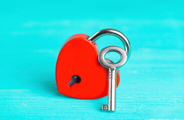 Red heart shaped padlock with silver key on blue