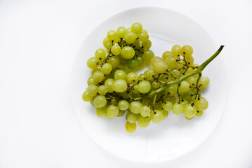 A bunch of green grapes on a white plate close-up.