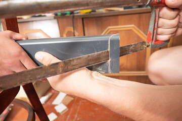 Trimming a wooden plinth with a manual jigsaw.